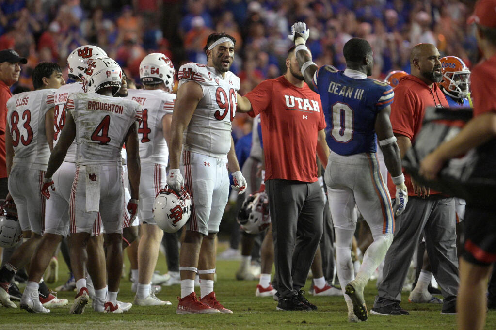 Utah defensive tackle Devin Kaufusi (90) reacts as Florida safety Trey Dean III (0) waves to Utah players after an NCAA college football game, Saturday, Sept. 3, 2022, in Gainesville, Fla. (AP Photo/Phelan M. Ebenhack)
