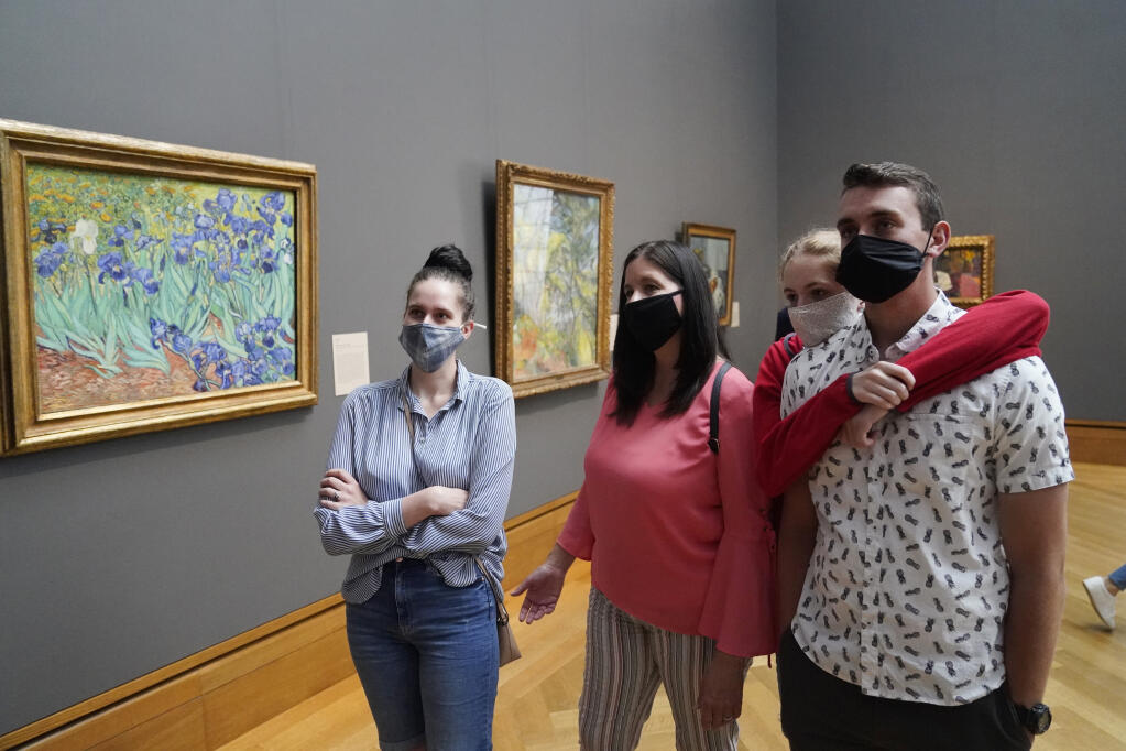 FILE - In this Wednesday, May 26, 2021 file photo, visitors wear masks as they view art, including Vincent van Gogh's "Irises", at left, at the newly re-opened Getty Center amid the COVID-19 pandemic in Los Angeles. (AP Photo/Marcio Jose Sanchez, File)