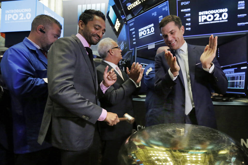 Social Capital Hedosophia Holdings Corp. CEO, Founder and Chairman Chamath Palihapitiya, left, is applauded by New York Stock Exchange president Tom Farley as he rings a ceremonial bell when his company's stock begins trading on the floor of the New York Stock Exchange, Thursday, Sept. 14, 2017. (AP Photo/Richard Drew)