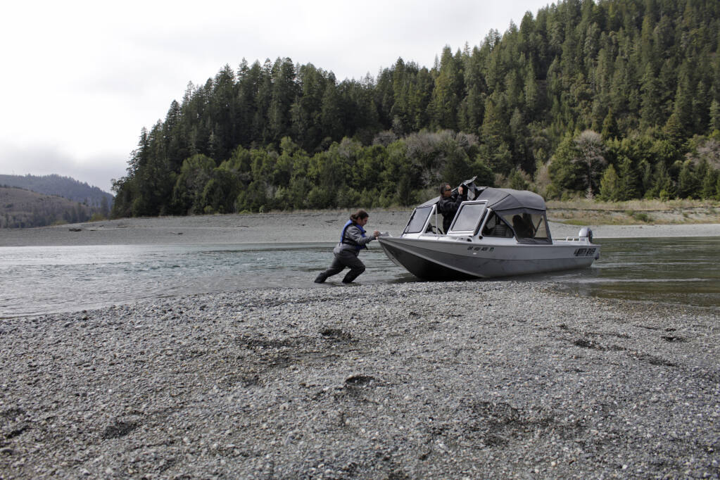 Hunter Maltz, a fish technician for the Yurok tribe, pushes a jet boat into the low water of the Klamath River at the confluence of the Klamath River and Blue Creek on March 5, 2020, as Keith Parker, as a Yurok tribal fisheries biologist, watches near Klamath in Humboldt County.  Federal officials announced Wednesday that farmers who rely on a massive irrigation project spanning the Oregon-California border will get 8% of the deliveries they need amid a severe drought. (Gillian Flaccus / Associated Press)