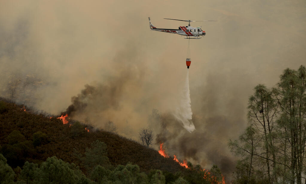 A Cal Fire helicopter makes a drop on the Hennessey fire, Monday, Aug. 17, 2020 in Napa County. (Kent Porter / The Press Democrat) 2020