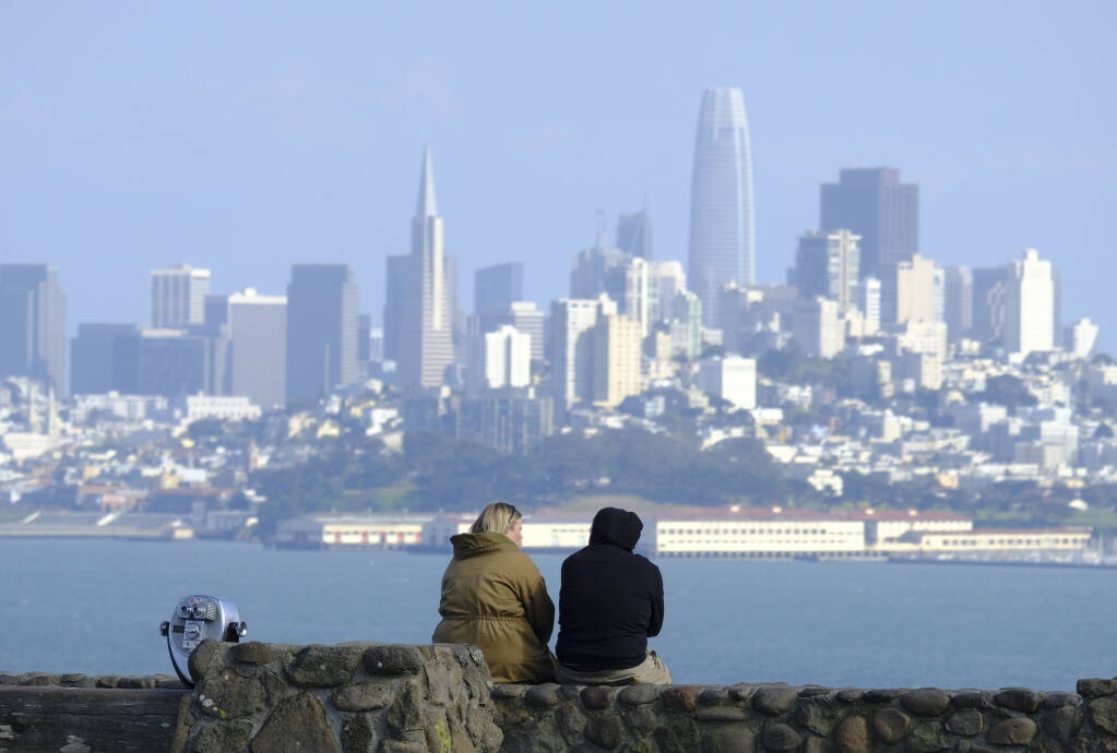 The view of the city from Marin County: A couple sits at a vista point with the San Francisco skyline in the background Friday, March 27, 2020, in Sausalito.(AP Photo/Eric Risberg)