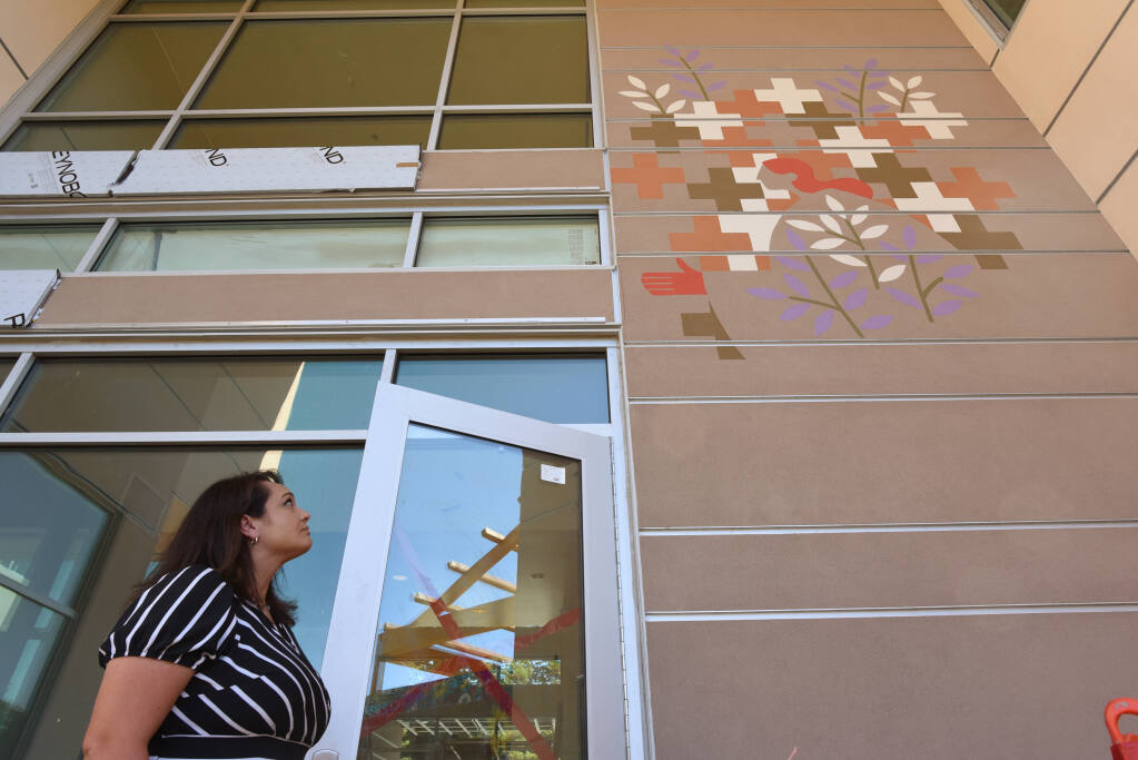 Catholic Charities Chief Programs Officer Jennielynn Holmes admires the design over the main entrance created by artist Martin Webb during a preview tour of the construction progress at Caritas Village, a 48,000 square foot family shelter, homeless drop-in center and health clinic developed by Catholic Charities and Burbank Housing and located in downtown Santa Rosa, Calif. on Friday, July 8, 2022.(Erik Castro / For The Press Democrat)