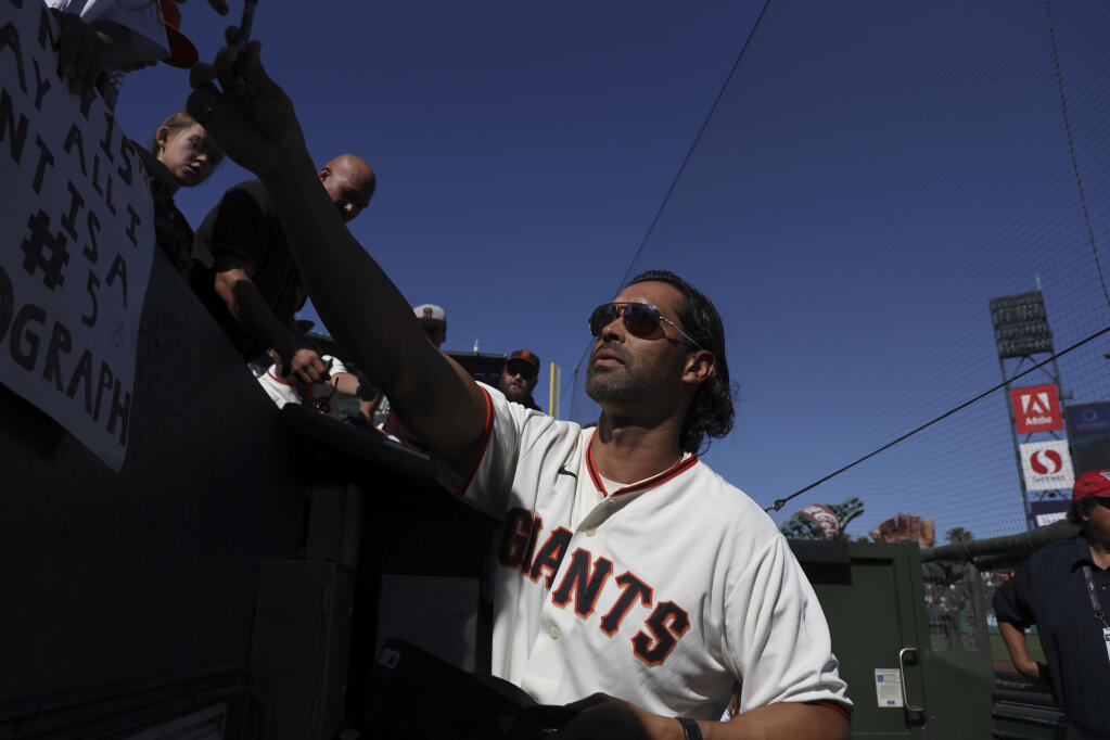 Former San Francisco Giants player Angel Pagan, a member of the 2012 World Series champion team, signs autographs before a game between the Pittsburgh Pirates and the Giants on Saturday, Aug. 13, 2022, in San Francisco. (AP Photo/Scot Tucker)