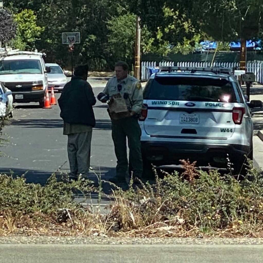 A Windsor police officer was spotted giving shoes to a man who is homeless Thursday, July 29, 2021. The officer's act of kindness is being praised on social media.   (Sonoma County Scanner Updates/Facebook)