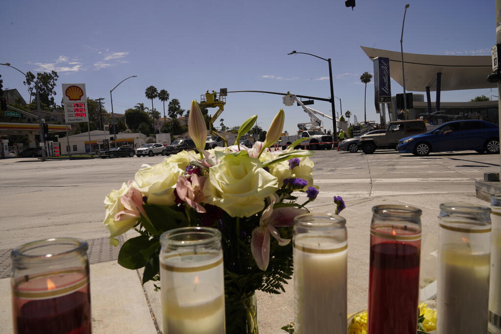Flowers and candles are left on an intersection after after crash involving as many as six cars near a gas station in the unincorporated Windsor Hills in Los Angeles, Friday, Aug. 5, 2022. A speeding car ran a red light and plowed into cars in a crowded intersection Thursday in a fiery crash that killed several people, including a baby, just outside of Los Angeles, authorities said. (AP Photo/Damian Dovarganes)