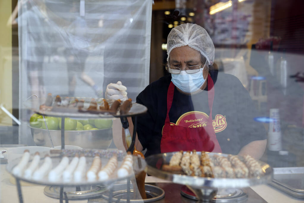 A worker wears a mask while prepares desserts at the Universal City Walk Friday, May 14, 2021, in Universal City. (AP Photo/Marcio Jose Sanchez)