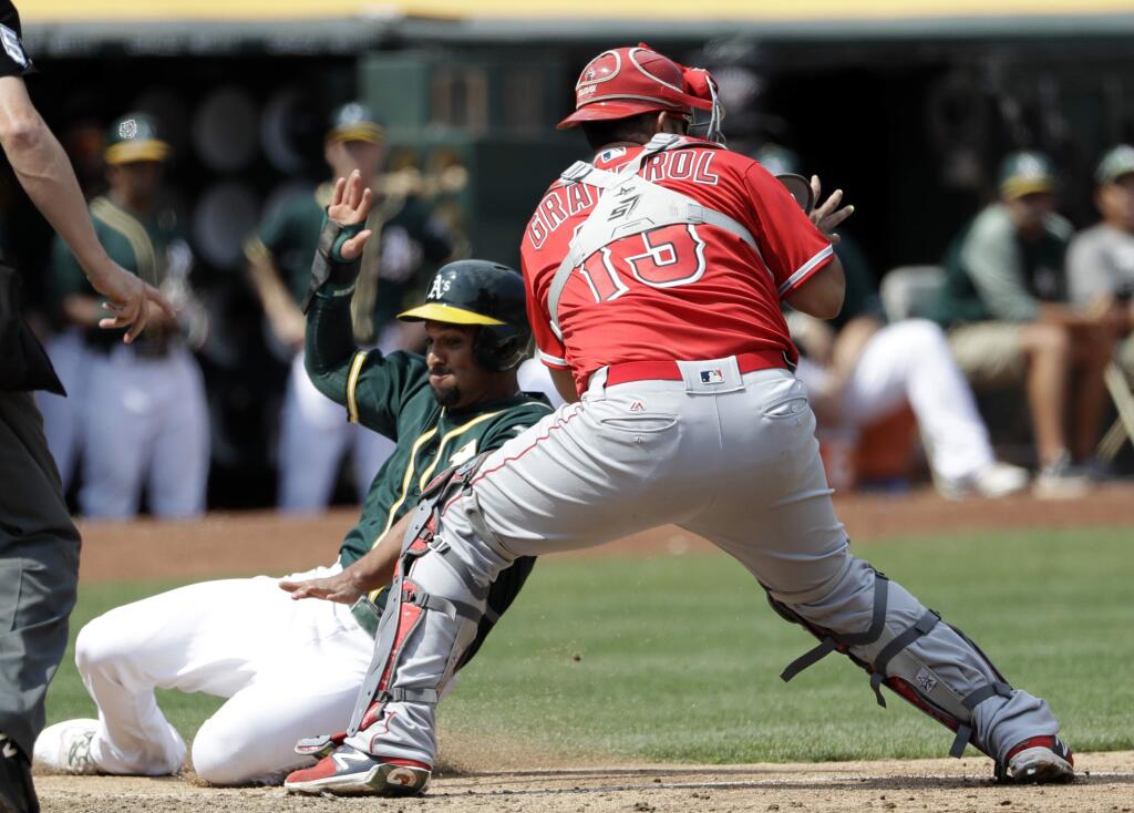 Oakland Athletics' Marcus Semien, left, scores past Los Angeles Angels catcher Juan Graterol (13) on a single by Chad Pinder during the fifth inning Wednesday, Sept. 6, 2017, in Oakland. (AP Photo/Marcio Jose Sanchez)