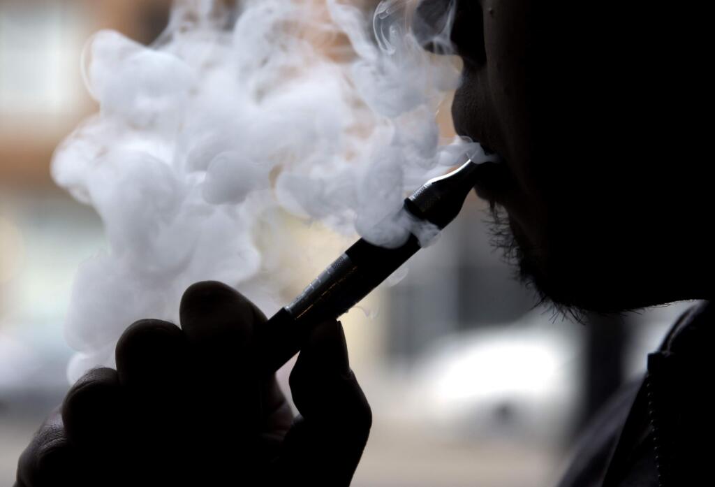 FILE - In this April 23, 2014, file photo, a man smokes an electronic cigarette in Chicago. On Thursday, May 5, 2016, the Food and Drug Administration released long-awaited rules that bring the burgeoning electronic cigarette industry under federal oversight. (AP Photo/Nam Y. Huh, File)