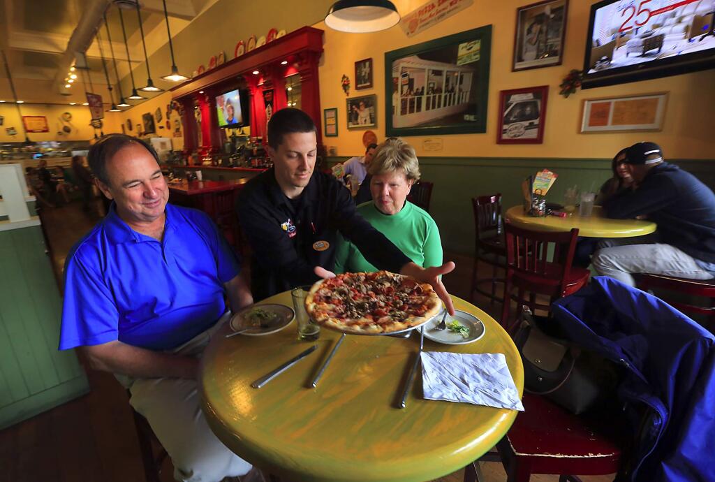 Daniel Hagar delivers a pizza to Dan and Ann Gladding at the downtown Santa Rosa Mary's Pizza Shack. (JOHN BURGESS/ PD FILE)