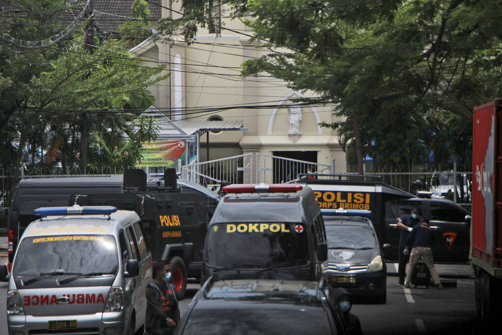 CORRECTS TO SAY ONE INSTEAD OF A FEW BOMBERS - Police vehicles are parked near a Catholic cathedral where an explosion went off in Makassar, South Sulawesi, Indonesia, Sunday, March 28, 2021. Police said at least one suicide bomber detonated outside the church on Indonesia's Sulawesi island, wounding several people. (AP Photo/Masyudi S. Firmansyah)