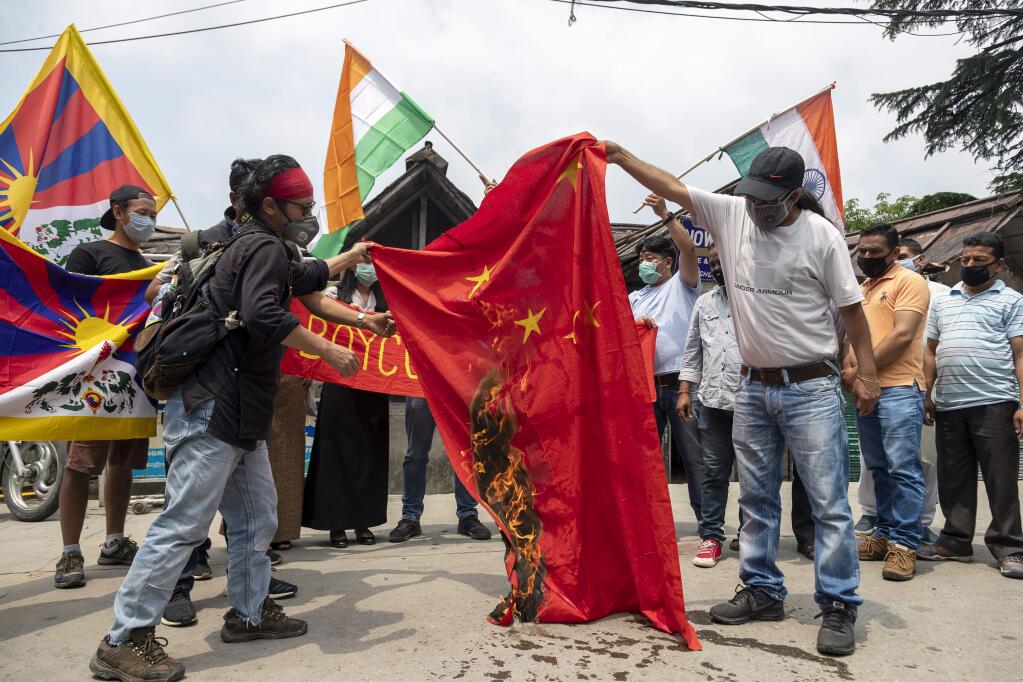 Exile Tibetans and local Indians burn a Chinese national flag during a protest in Dharmsala, India, Friday, June 19, 2020. India said Thursday it was using diplomatic channels with China to de-escalate a military standoff in a remote Himalayan border region where 20 Indian soldiers were killed this week. (AP Photo/Ashwini Bhatia)