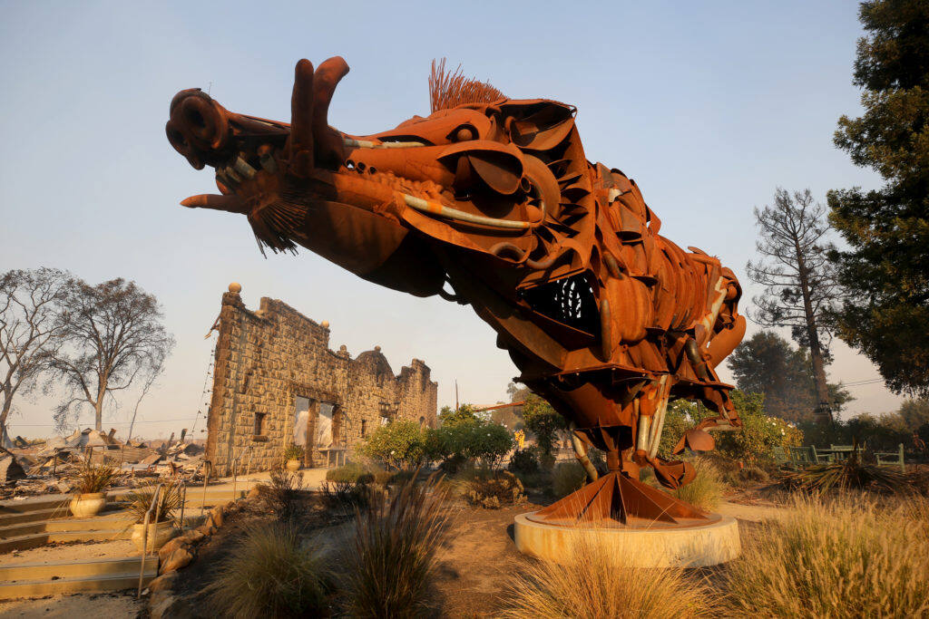 A sculpture of a wild boar called “Lord Snort” stands in front of the charred facade of Soda Rock Winery which burned during the Kincade fire in Healdsburg on Sunday, Oct. 27, 2019. (Beth Schlanker / The Press Democrat)