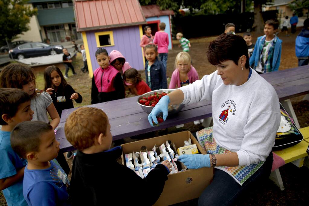 Kitchen manager Chandra Colley hands out snacks during recess on the first day of school at Kid Street Learning Center Charter School in Santa Rosa, California on Wednesday, August 20, 2014. (BETH SCHLANKER/ The Press Democrat)