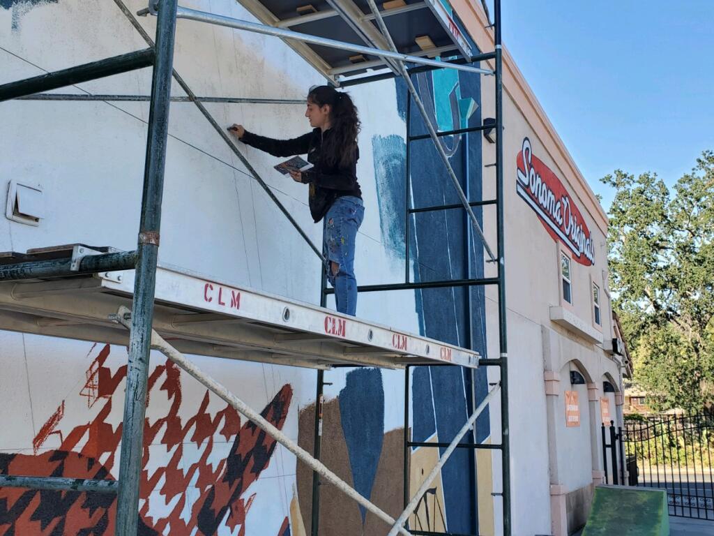 Rima Makaryan, co-founder of Sonoma County Artists Propelling Equity, works on a mural of local activist D’mitra Smith at Sonoma Originals skate shop in Boyes Hot Spring on Tuesday, June 9, 2021. (Remi Newman)
