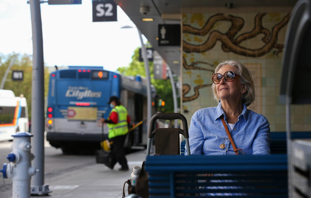 Eileen Memory waits for her bus to arrive at the transit mall in downtown Santa Rosa on Friday, June 17, 2022.  Memory has noticed the bus route cancellations due to bus operator shortage within Santa Rosa Transit.  (Christopher Chung/The Press Democrat)