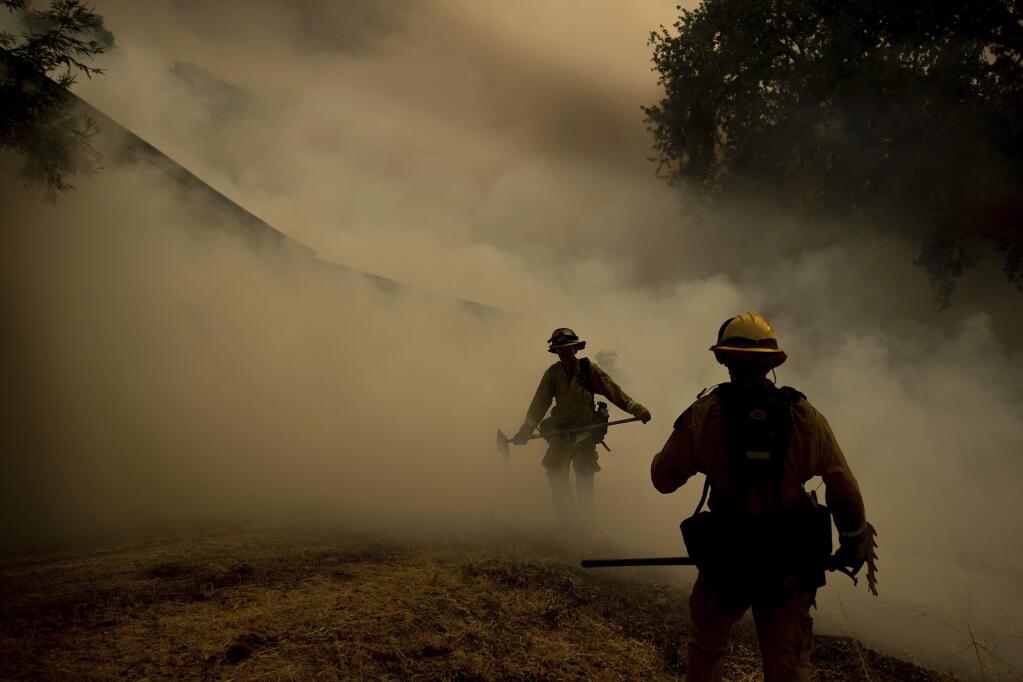 (FILE PHOTO) A firefighter walks through smoke while fighting to save Olof Cellars winery in Lakeport, Calif., Monday, July 30, 2018. (AP Photo/Noah Berger)