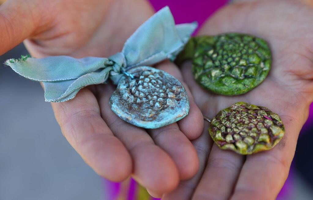Clay and epoxy pendants sent to Colleen and John Thill, from Wendy Anderson, that were made with imprints of pine cones from a tree at their burned Coffey Park home.(Christopher Chung/ The Press Democrat)