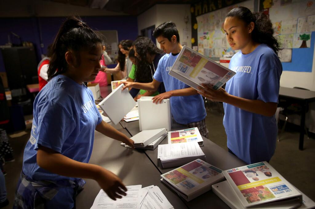 Nancy Trejo, right, Josue Lopez and Karen Hernandez put together binders for school readiness backpacks at Roseland University Prep, as part of its United Way day of service, in Santa Rosa on Wednesday, February 4, 2015. Students put together 1200 backpacks for three to four year old children.(Christopher Chung/ The Press Democrat)