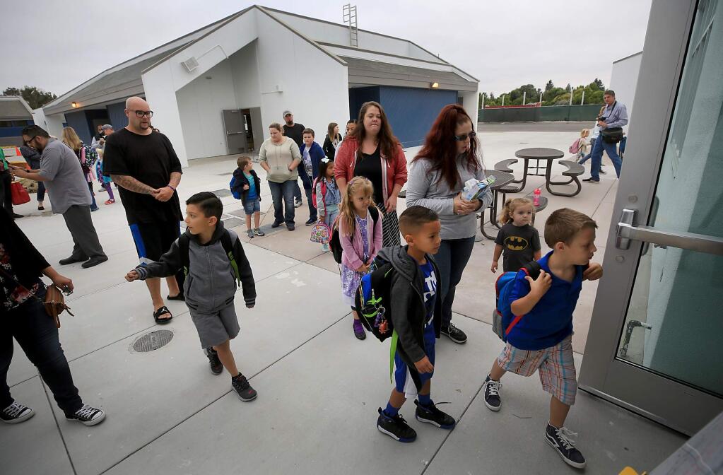 Flanked by their parents, first graders file in to class during the first day of school at the newly reopened Richard Crane Elementary School in Rohnert Park, Wednesday July 26, 2017. 15 years ago, a gaping $2 Million deficit and declining enrollment caused the Cotati-Rohnert park school district to close the school. With new housing projects in the works, officials decided to open the school. (Kent Porter / Press Democrat) 2017