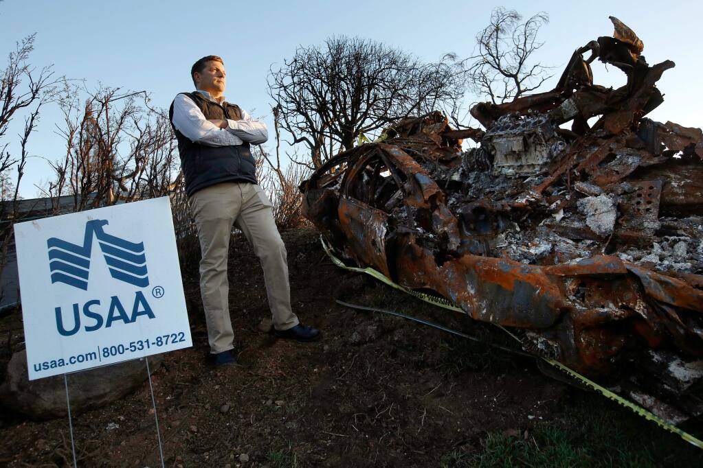 Robert Bivin stands beside the burned wreckage of two of his family's vehicles that were destroyed along with his Stony Oak Court home during the Tubbs Fire, in the Fountaingrove neighborhood of Santa Rosa, California on Thursday, December 21, 2017. Bivin is one of 10 USAA insurance customers who are suing the provider for deficient coverage and claim work in the aftermath of the October wildfires. (Alvin Jornada / The Press Democrat)
