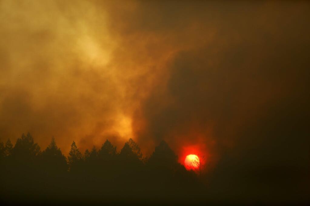 As the sun sets, smoke rises from the fire in Annadel State Park on Tuesday, October 10, 2017 in the Oakmont area of Santa Rosa, California . (BETH SCHLANKER/The Press Democrat)