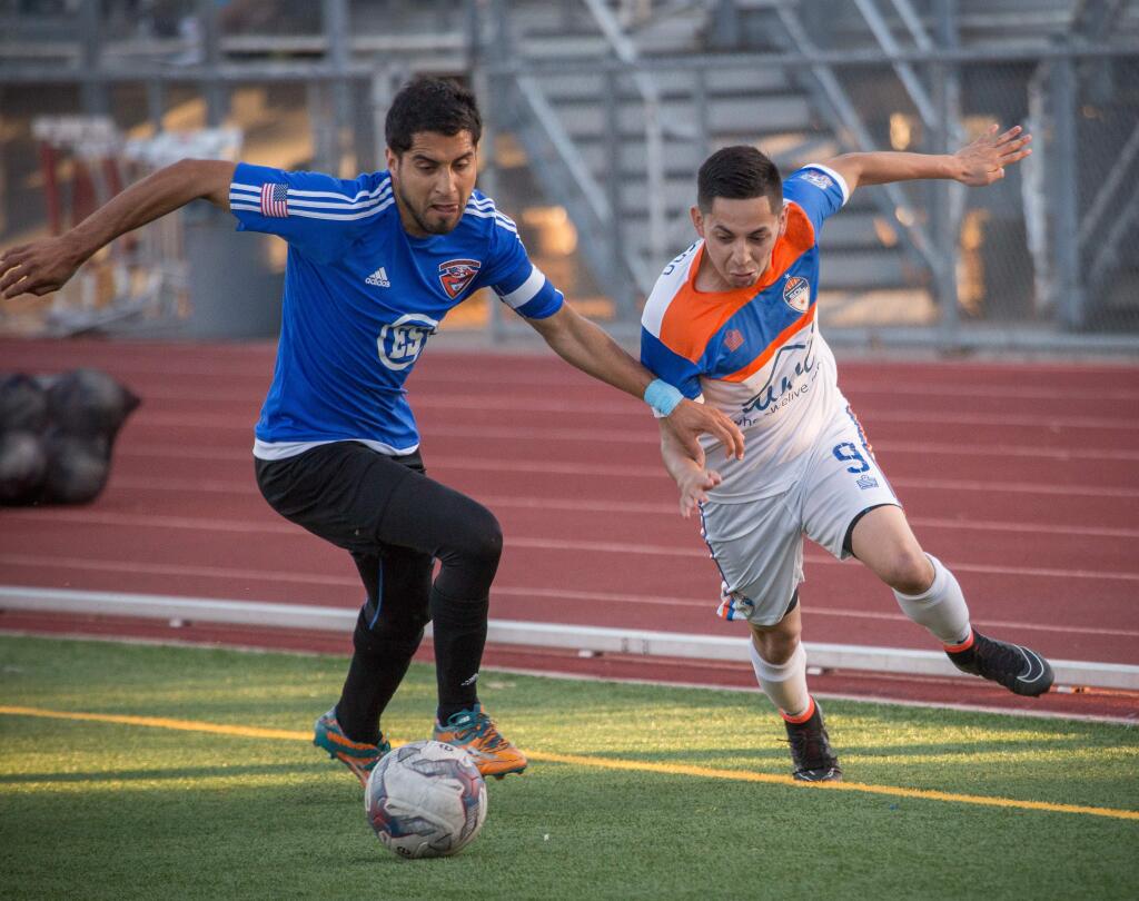 Sonoma County's Angel Acevedo, right, takes the ball around a CD Aguiluchos defender during their National Premier Soccer League regional semifinal playoff match at Santa Rosa High School in Santa Rosa, Saturday, July 18, 2015.
