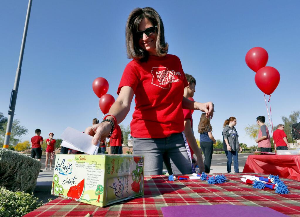 Teacher Jennifer Galluzzo casts her ballot outside Paseo Verde Elementary Wednesday, April 18, 2018 in Peoria, Ariz. Arizona teachers are weighing whether to walk out of their classrooms to demand more school funding after weeks of growing protests, a vote that's raising questions about how an unprecedented strike could play out across the state's education system. (AP Photo/Matt York)