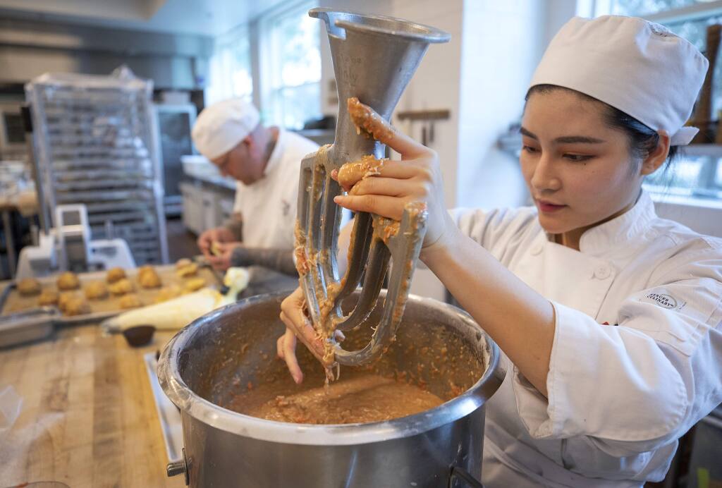 Shanying Zhu removes carrot cake batter from a mixing paddle in the production baking class at the SRJC Culinary Arts Center. Due to lower enrollment, the center will delay opening the Cafe Rose for regular lunches this semester. (photo by John Burgess/The Press Democrat)