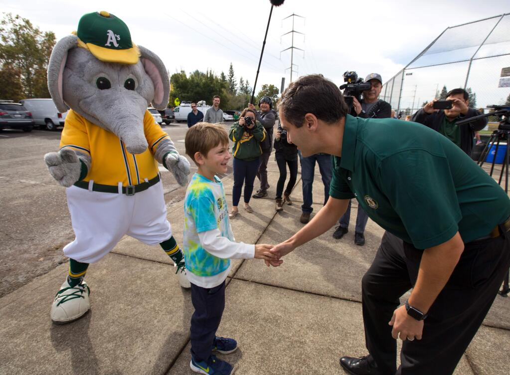 Loren Jade Smith, 9, of Santa Rosa, is greeted by Oakland A's President, Dave Kaval, and 'Stumper' the A's mascot at Mark West Little League's fields, in Santa Rosa, on Friday, Oct. 20, 2017. Loren received gifts from the A's and others after he wrote a letter about losing his home and A's memorabilia in the fires. (Photo by Darryl Bush / For The Press Democrat)