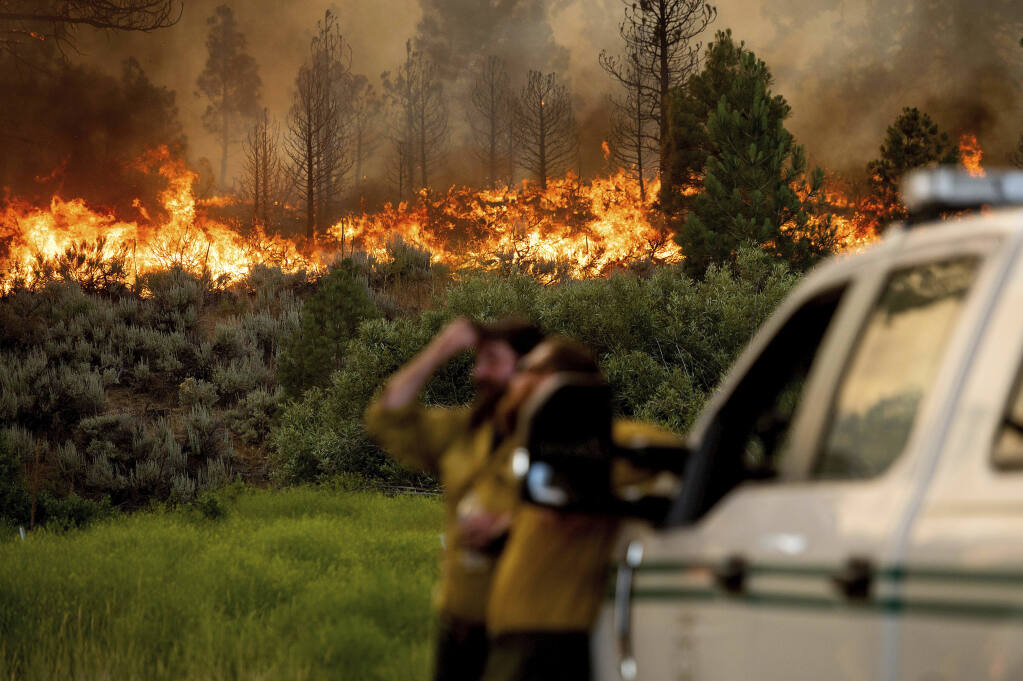 U.S. Forest Service firefighters Chris Voelker, left, and Kyle Jacobson monitor the Sugar Fire, part of the Beckwourth Complex Fire, burning in Plumas National Forest, Calif., on Friday, July 9, 2021. The Beckwourth Complex — a merging of two lightning-caused fires — headed into Saturday showing no sign of slowing its rush northeast from the Sierra Nevada forest region after doubling in size only a few days earlier. (AP Photo/Noah Berger)