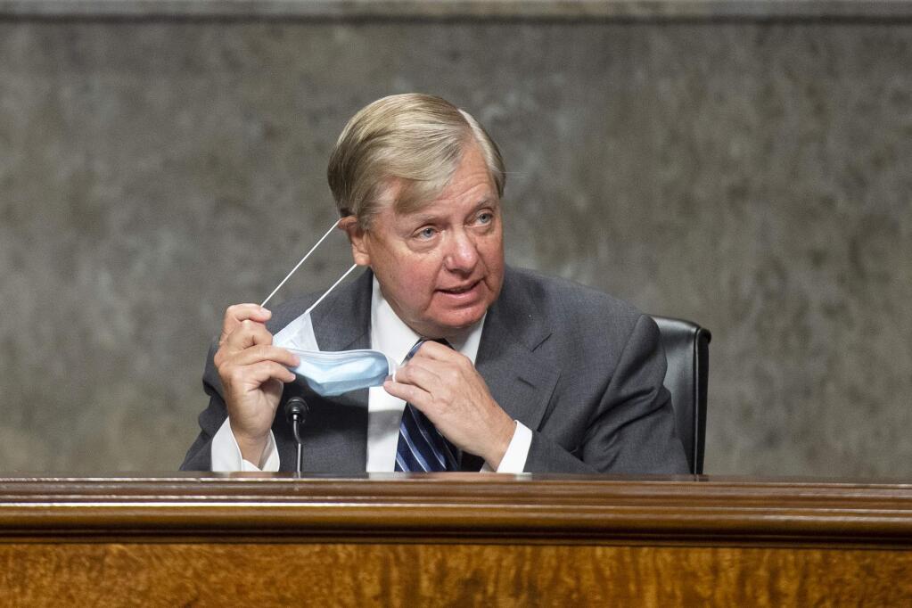 Chairman Lindsey Graham, R-S.C., takes off his mask as he arrives for the Senate Judiciary Committee hearing on 'Examining Liability During the COVID-19 Pandemic' on Capitol Hill in Washington on Tuesday, May 12, 2020. (Caroline Brehman/CQ Roll Call/Pool via AP)