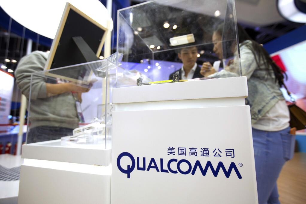 FILE - In this Thursday, April 27, 2017, file photo, visitors look at a display booth for Qualcomm at the Global Mobile Internet Conference (GMIC) in Beijing. (AP Photo/Mark Schiefelbein, File)