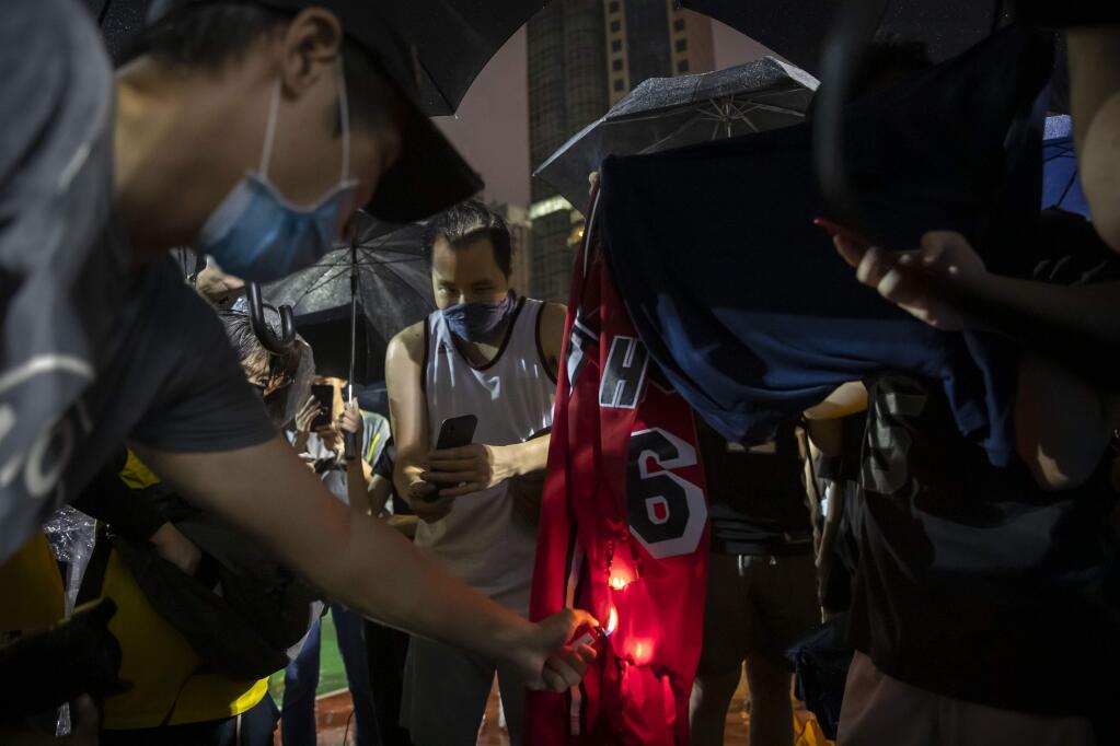 Demonstrators set a Lebron James jersey on fire during a rally at the Southorn Playground in Hong Kong, Tuesday, Oct. 15, 2019. Protesters in Hong Kong have thrown basketballs at a photo of LeBron James and chanted their anger about comments the Los Angeles Lakers star made about free speech during a rally in support of NBA commissioner Adam Silver and Houston Rockets general manager Daryl Morey, whose tweet in support of the Hong Kong protests touched off a firestorm of controversy in China. (AP Photo/Mark Schiefelbein)