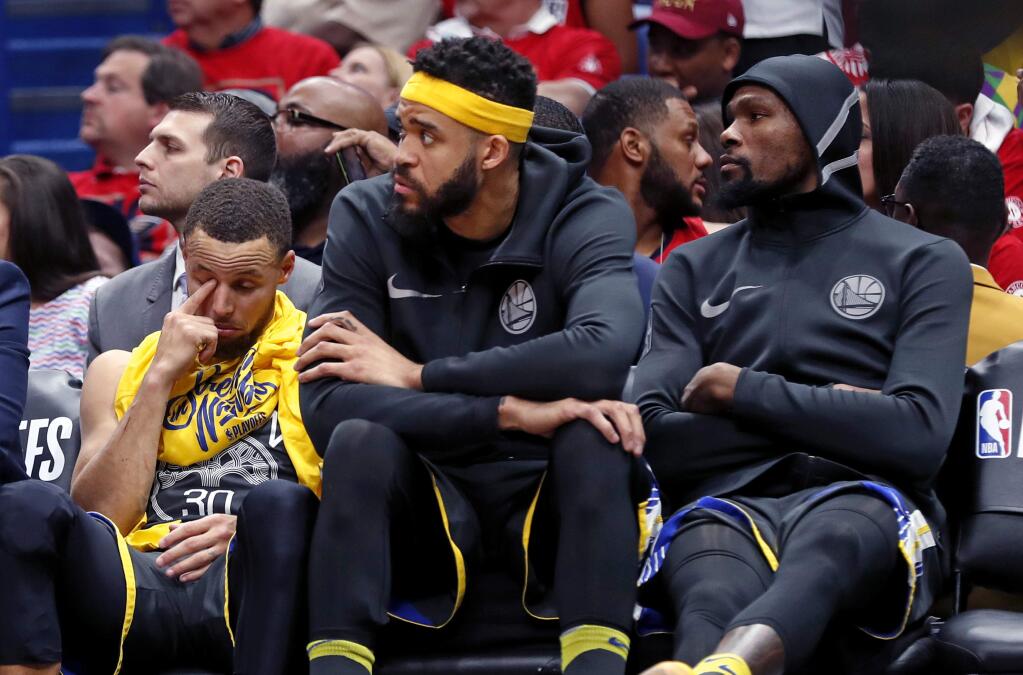 Golden State Warriors guard Stephen Curry, left, center JaVale McGee and forward Kevin Durant, right, sit on the bench during the second half of Game 3 of a second-round playoff series against the New Orleans Pelicans in New Orleans, Friday, May 4, 2018. (AP Photo/Gerald Herbert)