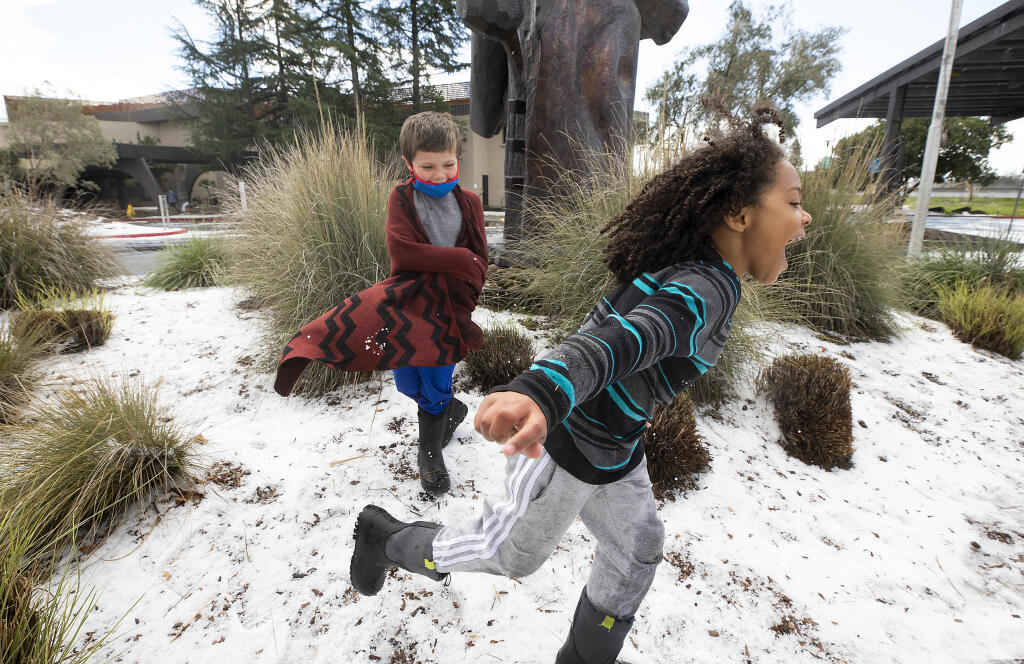 John Wallace, 6, runs away from a snowball thrown by Jaxson Pelton, 6, in a patch of hail at the Luther Burbank Center in Santa Rosa on Wednesday morning, March 10, 2021.  (John Burgess / The Press Democrat)