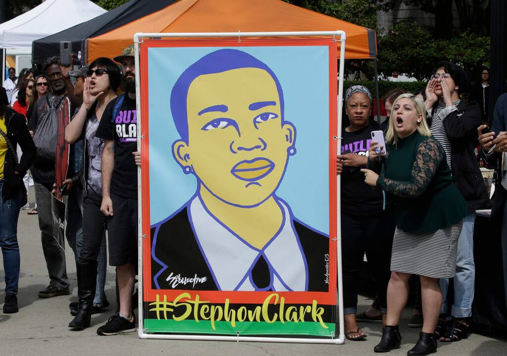 FILE - In this April 9, 2018 file photo protesters display an image of Stephon Clark at a crime victims rights rally, at the Capitol in Sacramento, Calif. Two Sacramento police officers won't face criminal charges for the fatal shooting of Clark following a chase that ended in his grandparents' yard and started a series of angry protests that roiled California's capital city, the county's top prosecutor announced Saturday, March 2, 2019, following a nearly yearlong investigation. (AP Photo/Rich Pedroncelli,File)