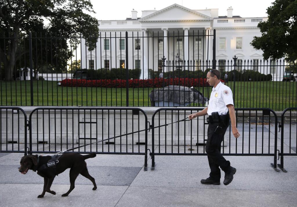 A member of the Secret Service Uniformed Division with a K-9 walks along the perimeter fence along Pennsylvania Avenue outside the White House in Washington, Monday, Sept. 22, 2014. The Secret Service tightened their guard outside the White House after Friday's embarrassing breach in the security of one of the most closely protected buildings in the world. A man is accused of scaling the White House perimeter fence, running across the lawn and entering the presidential mansion before agents stopped him. (AP Photo/Carolyn Kaster)
