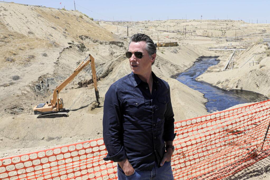 FILE - In this July 24, 2019, file photo, Gov. Gavin Newsom tours the Chevron oil field west of Bakersfield where a spill of more than 800,000 gallons flowed into a dry creek bed in McKittrick, Calif. Newsom's administration has temporarily banned new oil wells in California if they use an extraction method that is linked to an ongoing oil spill in Kern County. On Tuesday, Nov. 19, 2019, the Division of Oil, Gas and Geothermal Resources announced it will not approve new oil wells that use high-pressure steam to soften the thick crude underground so it can flow more easily. (Irfan Khan/Los Angeles Times via AP, Pool, File)