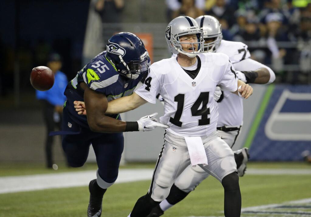 Seattle Seahawks defensive end Frank Clark (55) causes Oakland Raiders quarterback Matt McGloin (14) to fumble in the first half of a game, Thursday, Sept. 3, 2015, in Seattle. defensive tackle Jordan Hill recovered the ball in the end zone for a touchdown. (AP Photo/Elaine Thompson)
