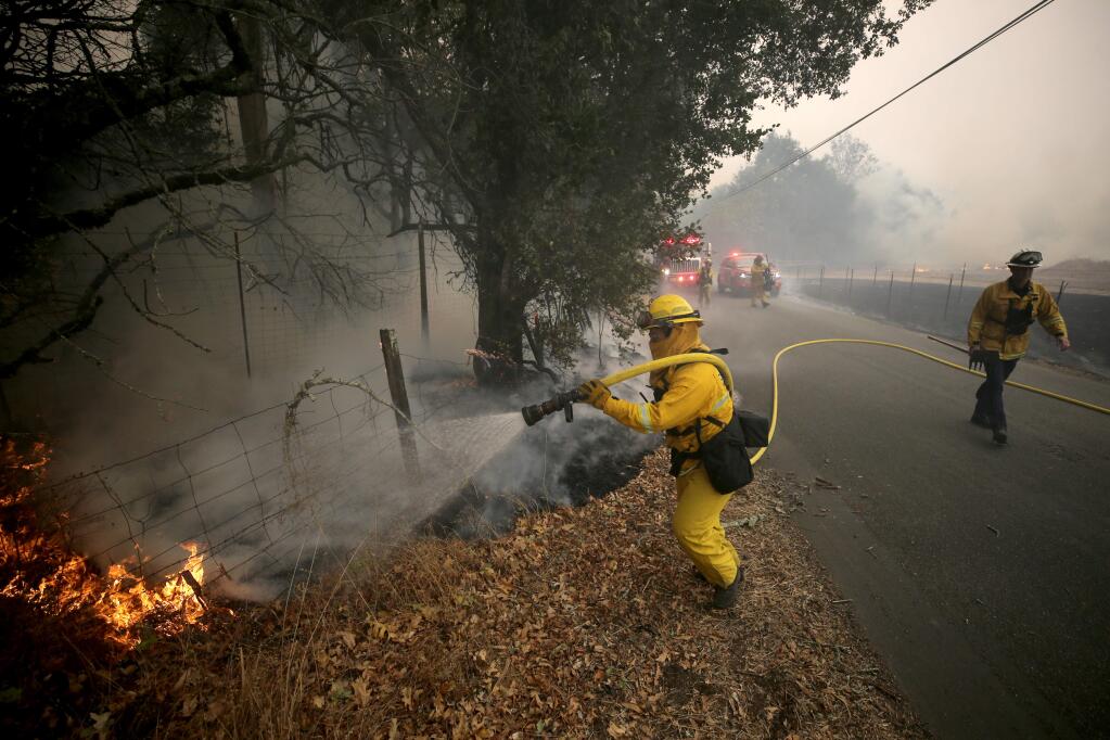 A Santa Rosa firefighter rushes to put out a spot fire on Brooks Rd North during the Kincade fire in Windsor on Sunday, October 27, 2019. (BETH SCHLANKER/ The Press Democrat)