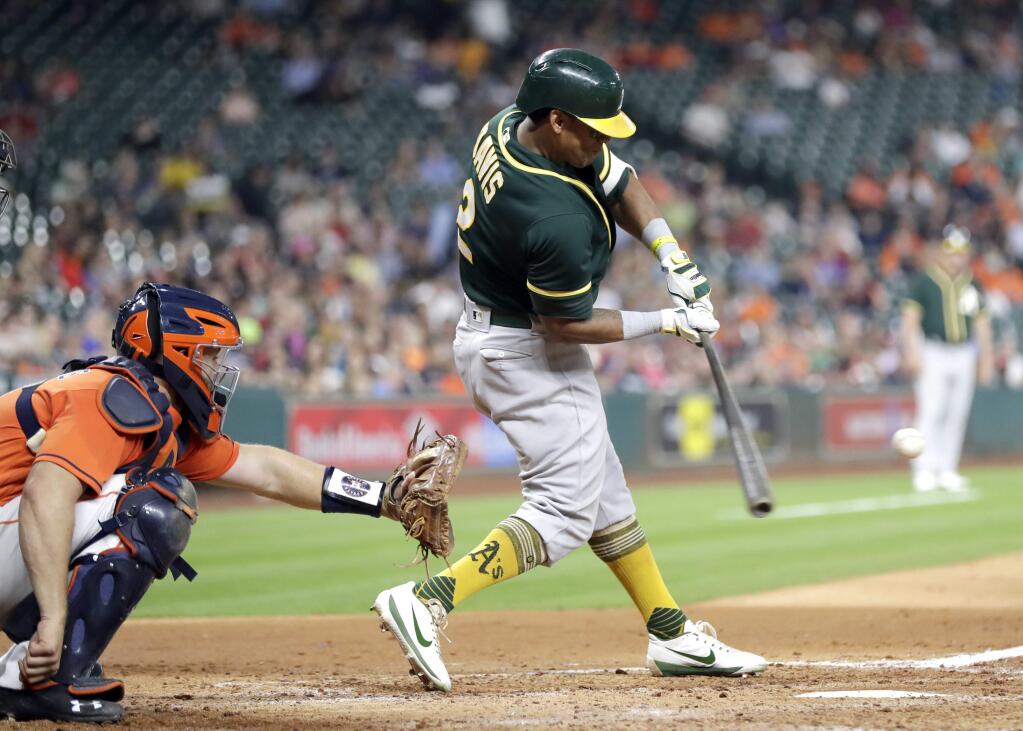 The Oakland Athletics' Khris Davis hits a home run as Houston Astros catcher Evan Gattis reaches for the pitch during the third inning Friday, April 28, 2017, in Houston. (AP Photo/David J. Phillip)