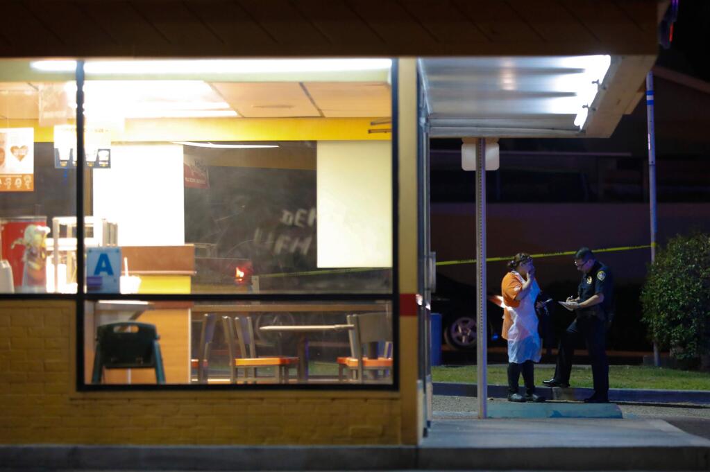 San Diego Police officers begin questioning witnesses after a shooting outside the Church's Chicken eatery in San Diego, Calif., Wednesday, Nov. 6, 2019. Authorities say the shooting happened Wednesday evening at a Church's Chicken in the Otay Mesa area. San Diego Police Officer John Buttle tells KNSD-TV the suspected gunman had been in the restaurant earlier in the day, when he tried to pay with a counterfeit bill. (Nelvin C. Cepeda/The San Diego Union-Tribune via AP)