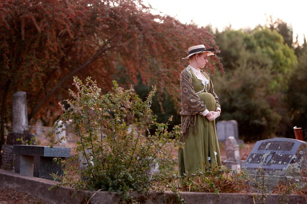 Christine Vondralee, portraying a pregnant Matilda Williamson, looks at the real gravestone of her character during the Sebastopol Cemetery Walk, presented by the Western Sonoma County Historical Society, in Sebastopol, California on Friday, October 7, 2016. (Alvin Jornada / The Press Democrat)