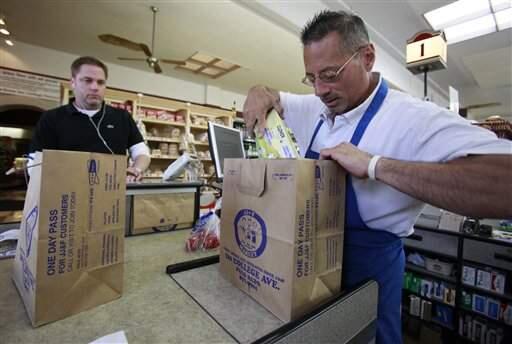 Grocery store clerk Mike Saladino places a customer's purchased items in a paper bag in Palo Alto on Wednesday, June 2, 2010. It’s been nearly five years since California voters banned single-use plastic bags. Now, many grocers use a more robust plastic that technically meets standards, but has raised concern among environmental groups. (ASSOCIATED PRESS/PAUL SAKUMA)