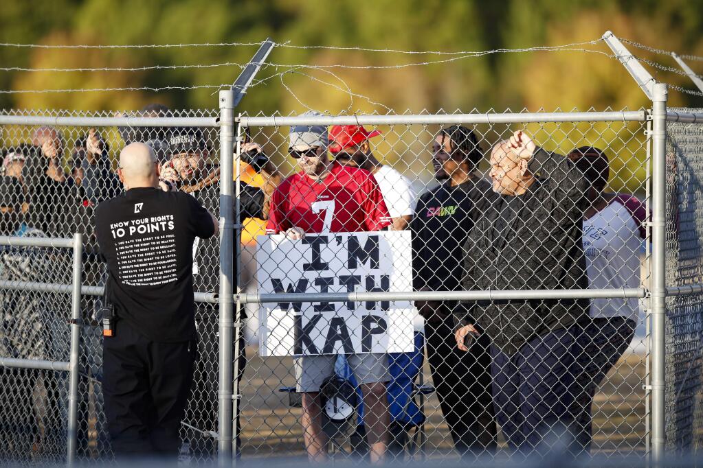 Fans watch from behind a fence as free agent quarterback Colin Kaepernick participates in a workout for NFL football scouts and media, Saturday, Nov. 16, 2019, in Riverdale, Ga. (AP Photo/Todd Kirkland)