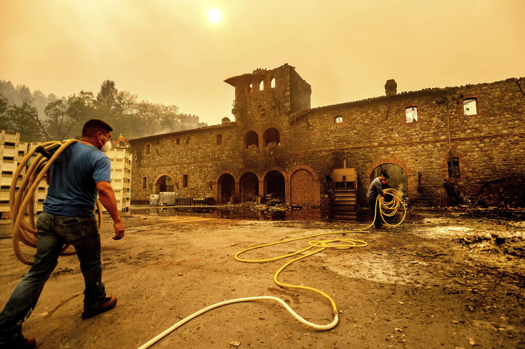 Winery workers Carlos Perez, left, and Jose Juan Perez extinguish hotspots at Castello di Amorosa, Monday, Sept. 28, 2020, in Calistoga. The winery was damaged in the Glass Fire. (AP Photo/Noah Berger)