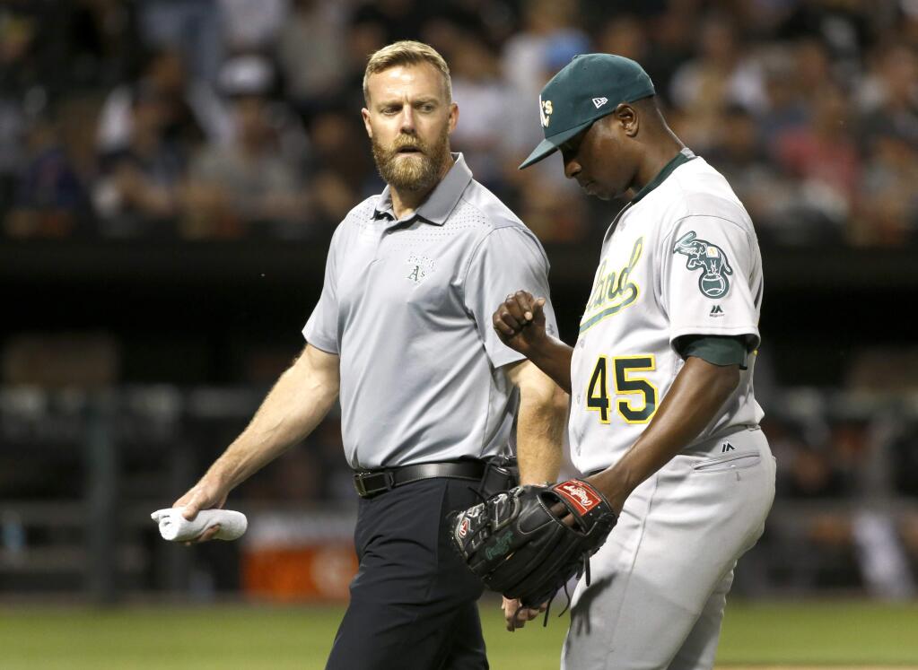 Oakland Athletics starter Jharel Cotton, right, leaves the game looking at his pitching thumb with a member of the medical staff during the sixth inning against the Chicago White Sox, Friday, June 23, 2017, in Chicago. (AP Photo/Charles Rex Arbogast)