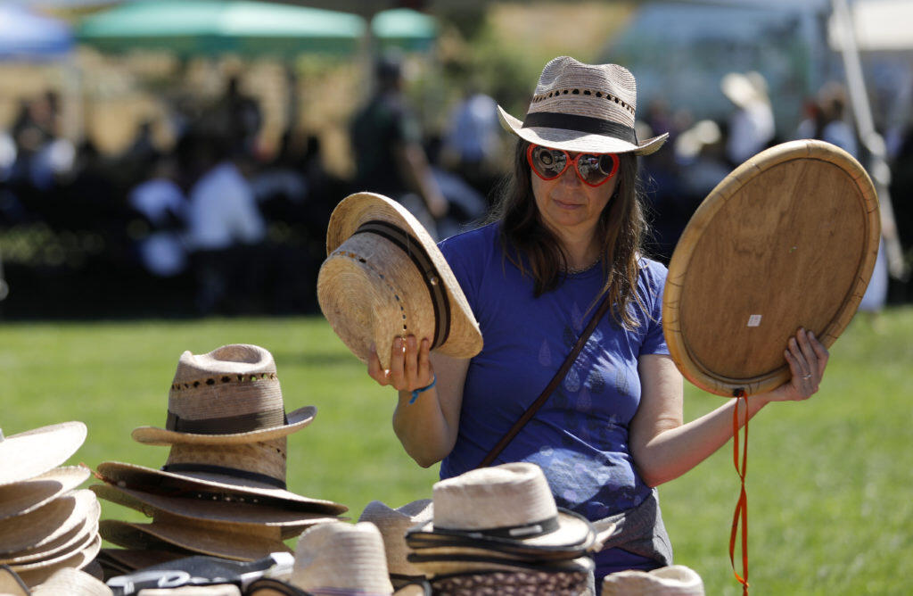 Lea Rude tries on a variety of hats for sale during the Guelaguetza Tierra del Sol at the Luther Burbank Center for the Arts in Santa Rosa on Sunday, July 15, 2018. (Beth Schlanker/ The Press Democrat)