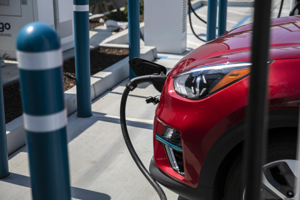 An electric vehicle charges at a station in Millbrae. Photo by Martin do Nascimento, CalMatters